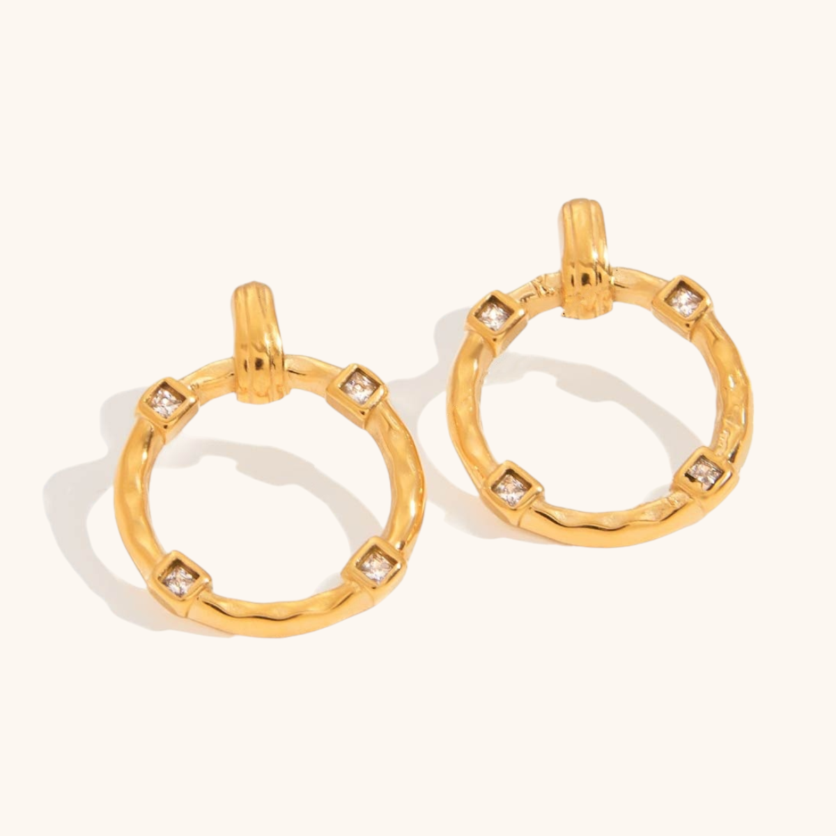 Flatlay of hammered gold hoop earrings with clear stones