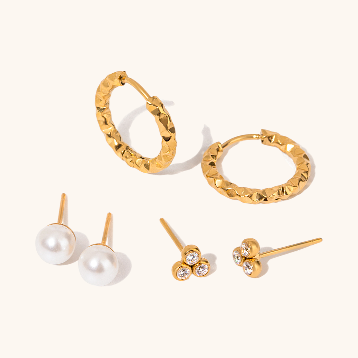 Gold hammered hoop earrings with a bold sculptural finish on white backdrop