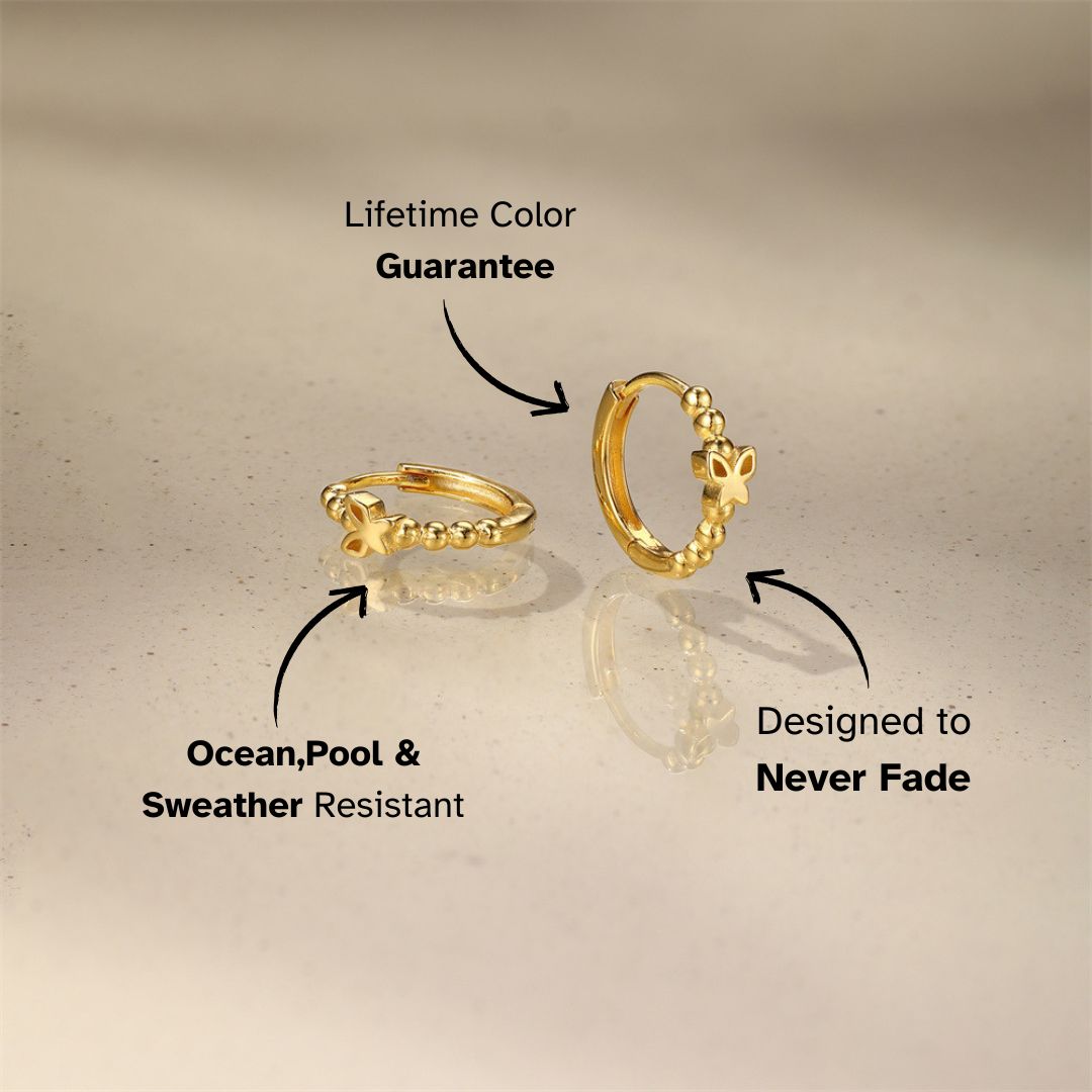 Minimal gold huggie earrings with flower details and textured bead design on neutral surface