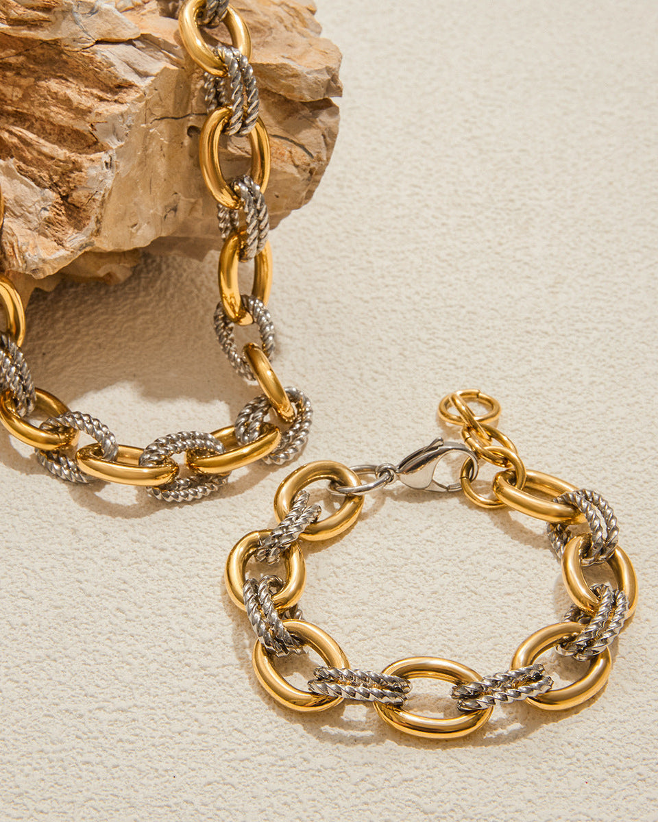 Gold and silver chain bracelet on a textured beige surface