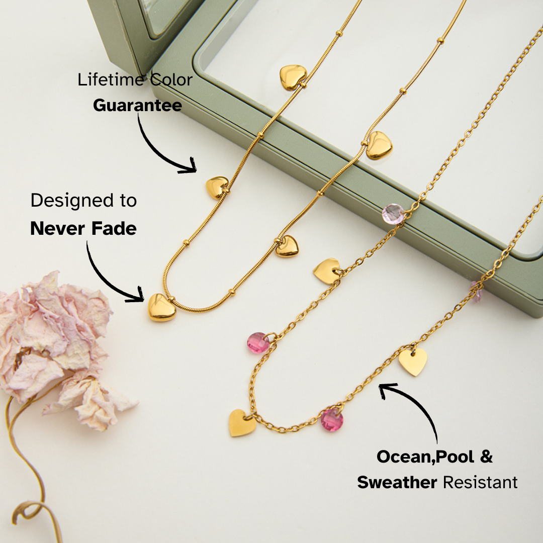 Gold necklace with heart-shaped pendants on a light gray background