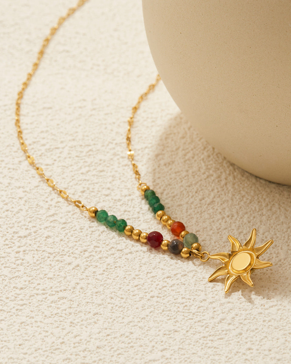 Necklace with sun charm and colored beads on a textured surface