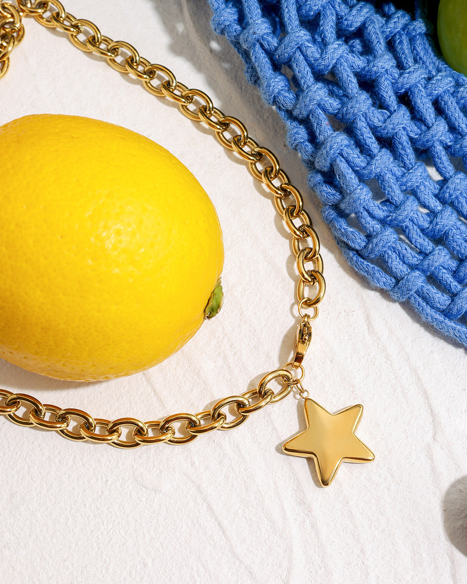 Trendy gold star necklace with blue fabric and berries, lemon accent, modern setup.