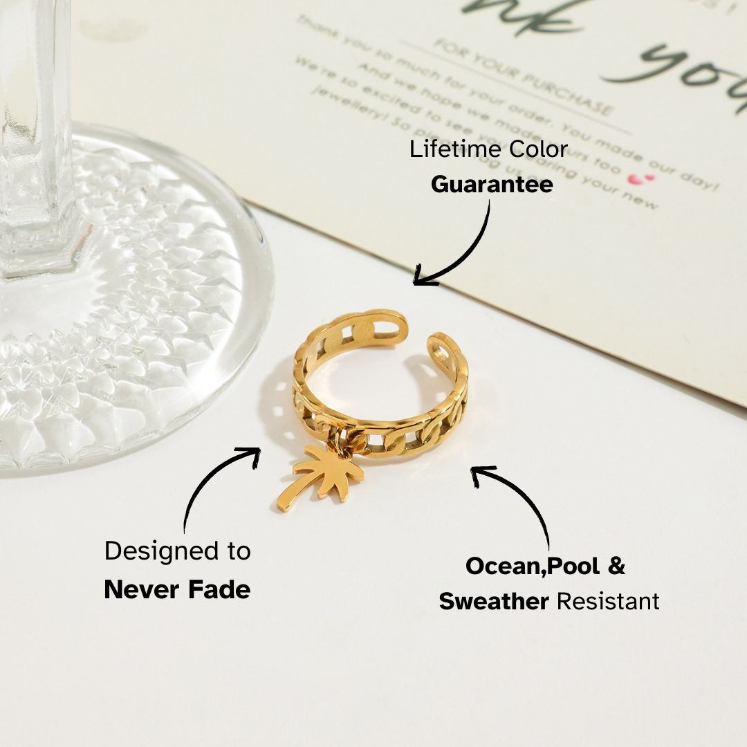 Palm pendant gold chain ring placed beside a drink glass and thank you card