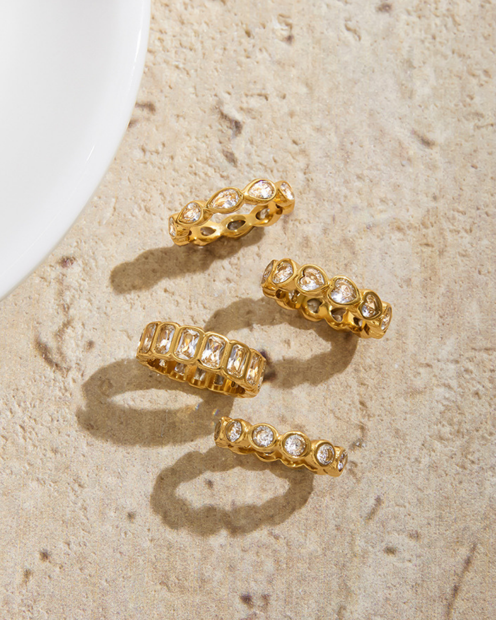 Set of gold rings with gemstones on a textured beige surface