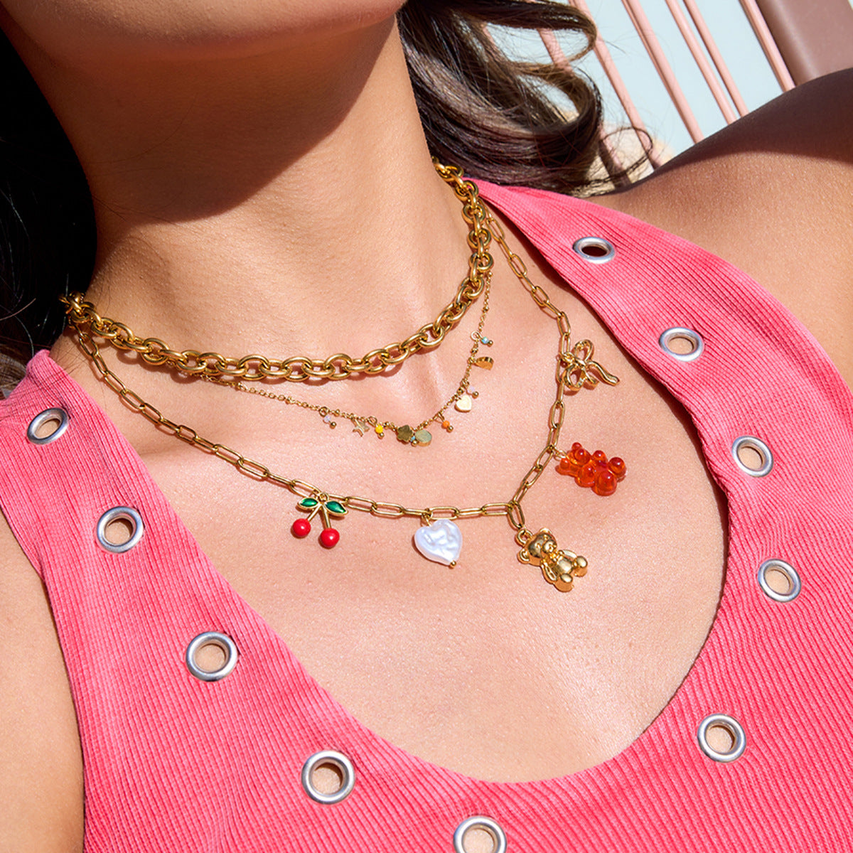 layered gold charm necklace worn with pink dress