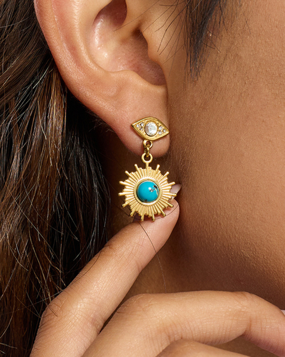 Gold earring with turquoise stone worn by a person
