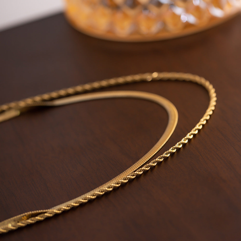 Gold rope and snake chain necklace laid flat on a dark wood surface with vintage vibe