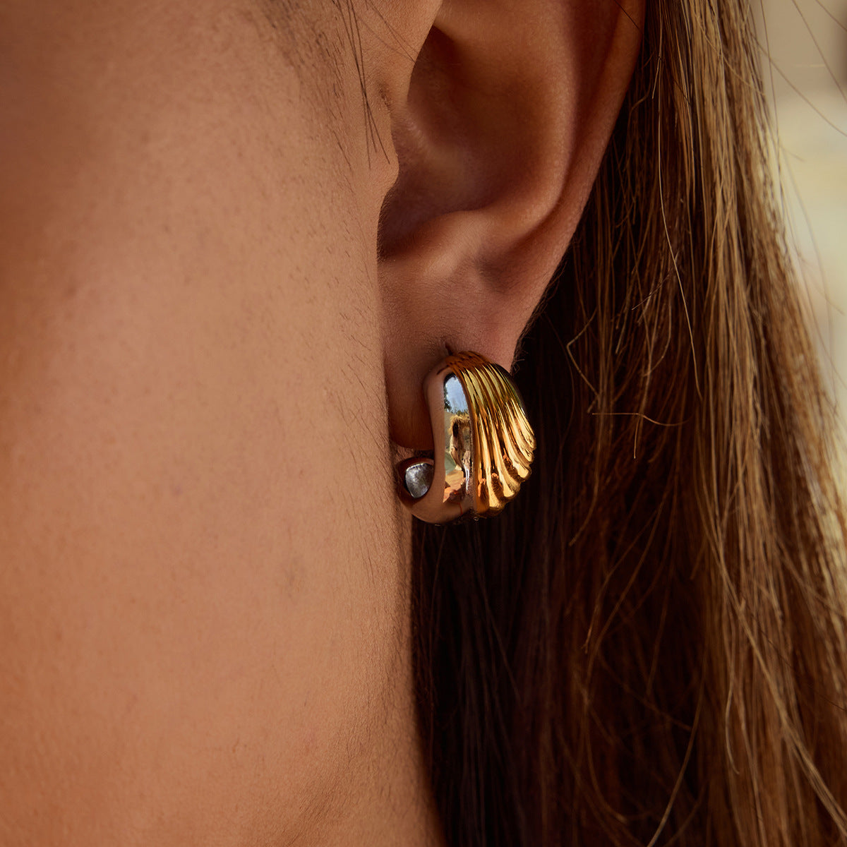 Model wearing thick wavy earrings under sunlight