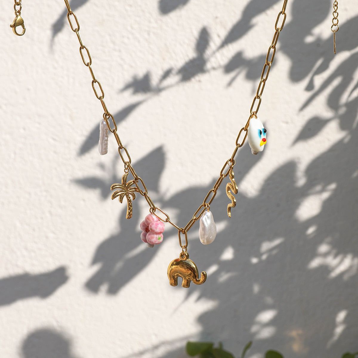 Close-up of vacation style necklace featuring bold gold links and multi-color pendants