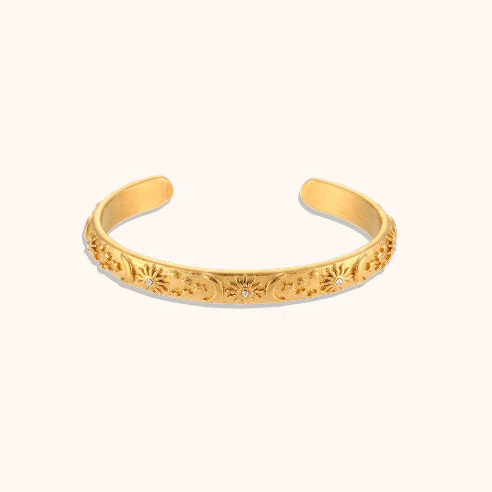 Elegant gold cuff bracelet with engraved sun and moon motifs and vintage floral details