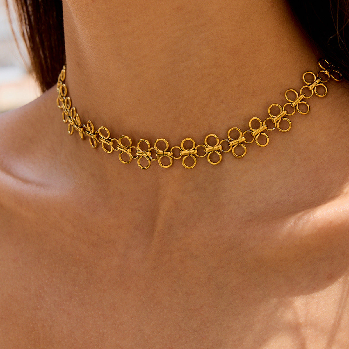 Woman wearing gold floral choker layered with charm necklaces