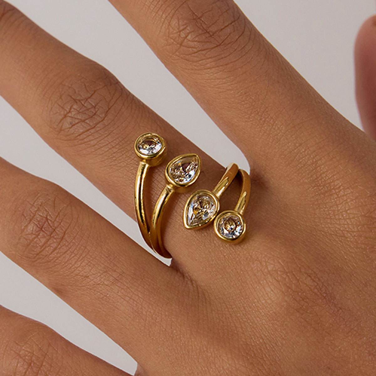 Elegant crystal gold ring worn on model’s finger with nude nails