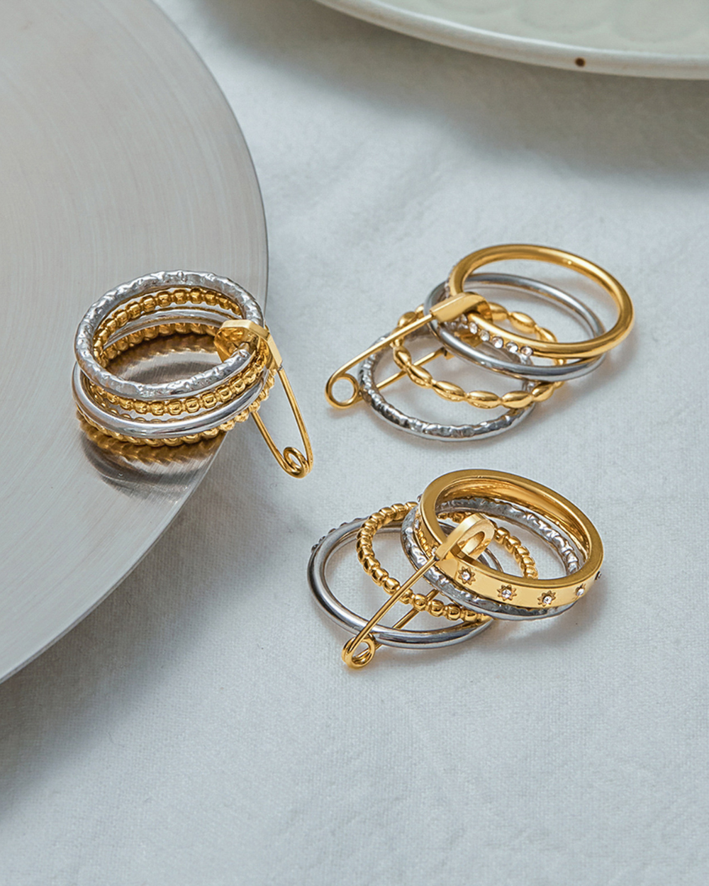 Gold and silver circular earrings on a light gray surface