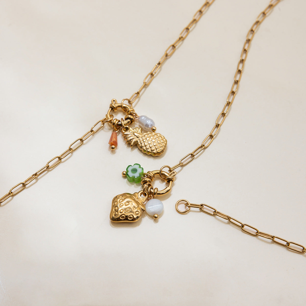 Gold chain necklace with various charms on a light beige background
