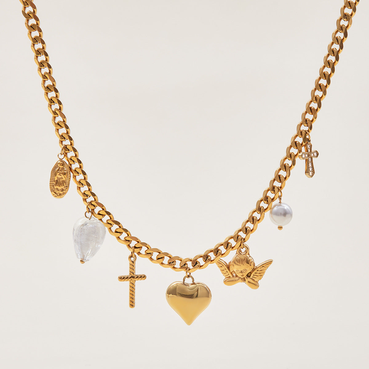 Gold charm bracelet with heart, cross, and angel pendants