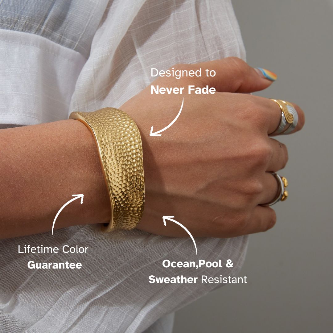 Close-up of a golden cuff bracelet with a hammered texture and reflective polish under bright lighting