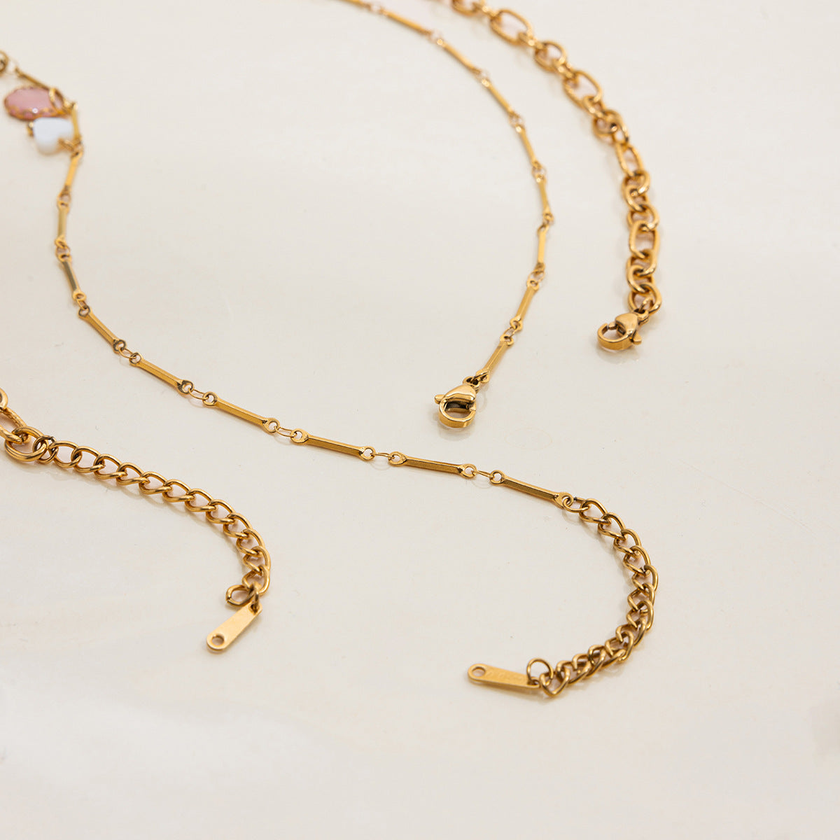 Flatlay of two vintage-style gold necklaces with feminine, romantic charms
