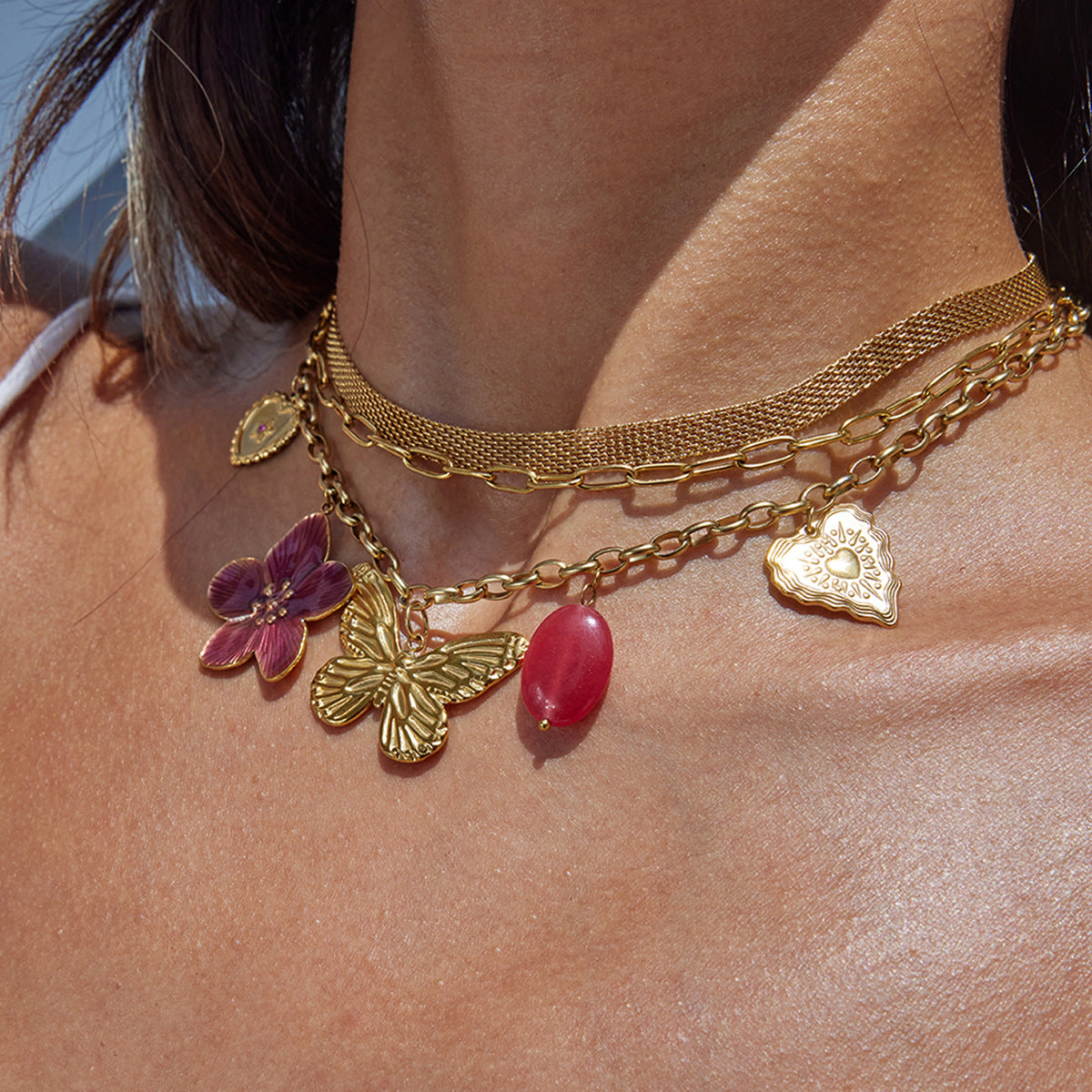 Model wearing layered gold necklace with butterfly and flower charms