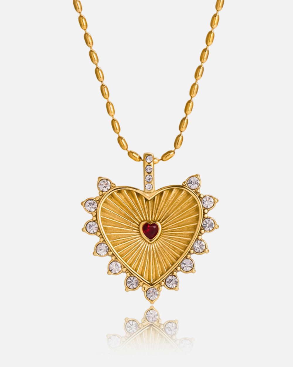 Gold heart-shaped necklace with a red heart in the center on a white background