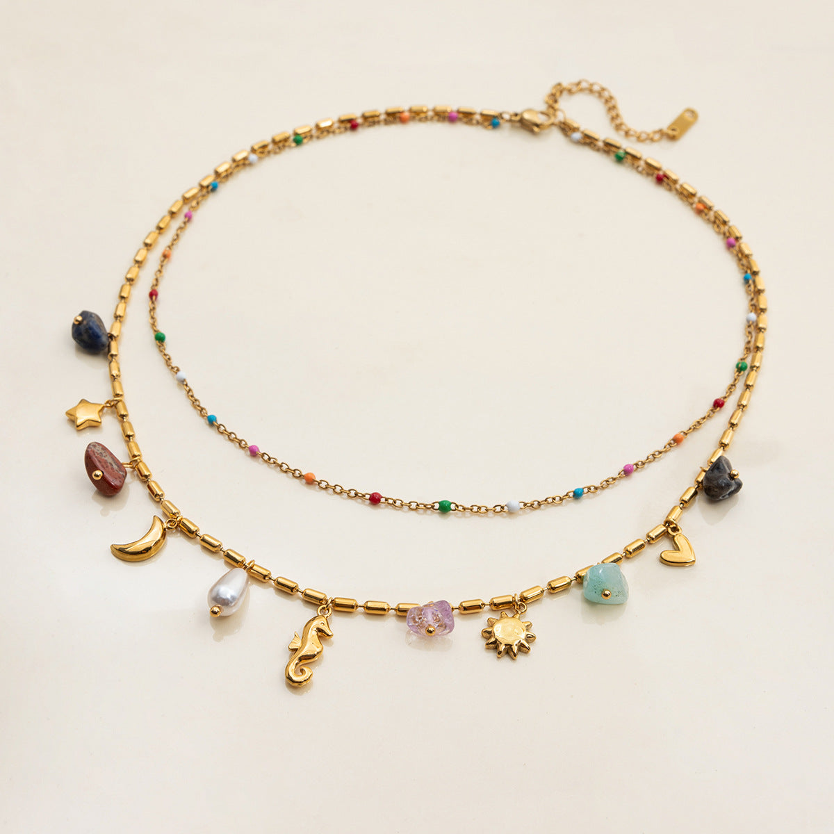 Gold necklace with various charms on a light beige background
