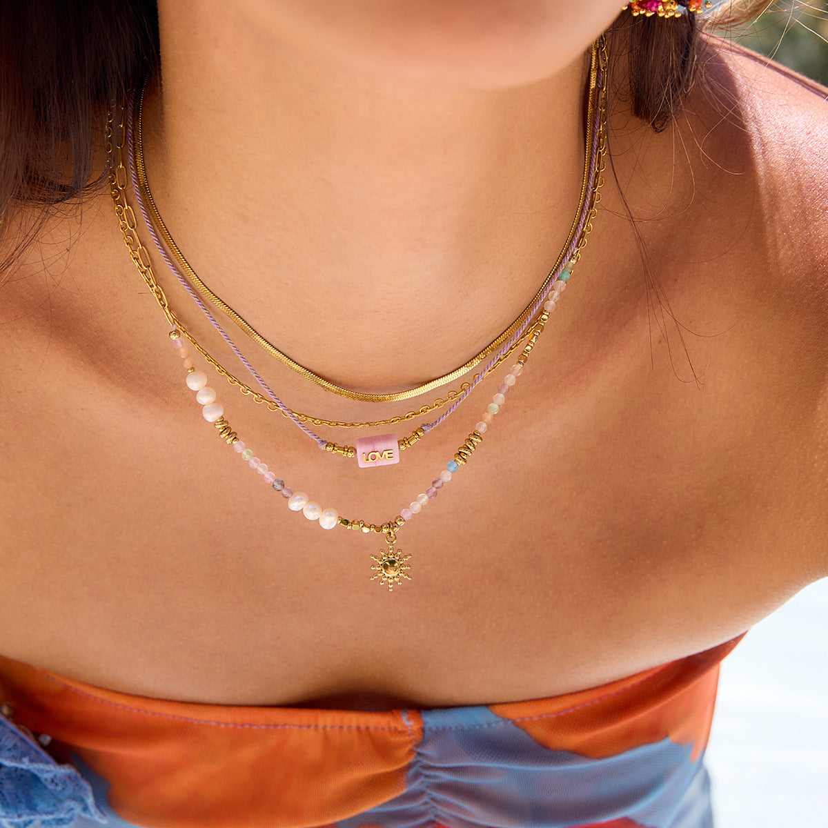 Model wearing colorful beaded sun pendant necklace at the beach