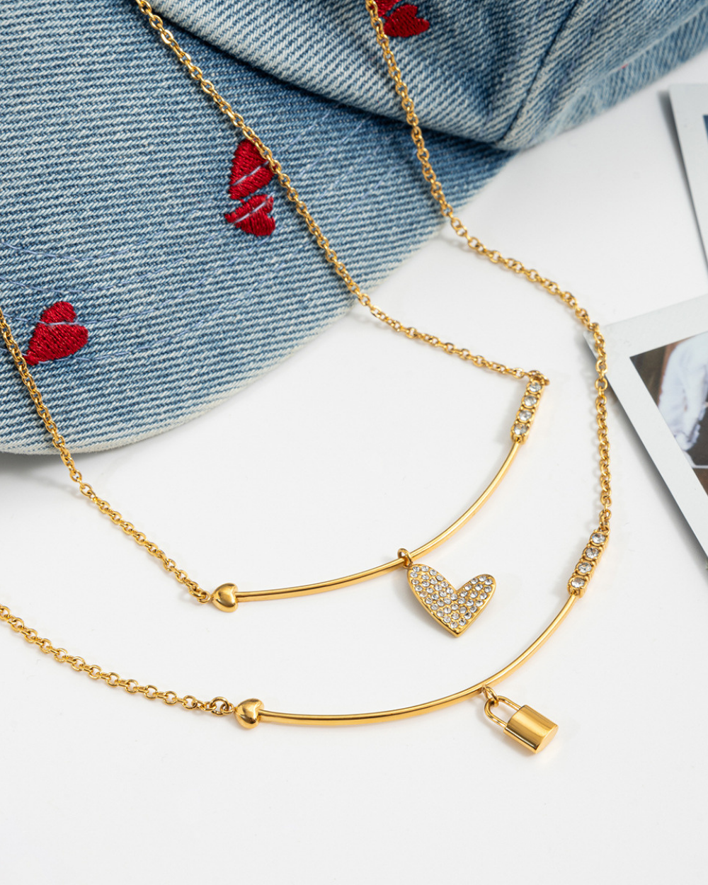 Gold necklace with heart charm on a denim fabric background