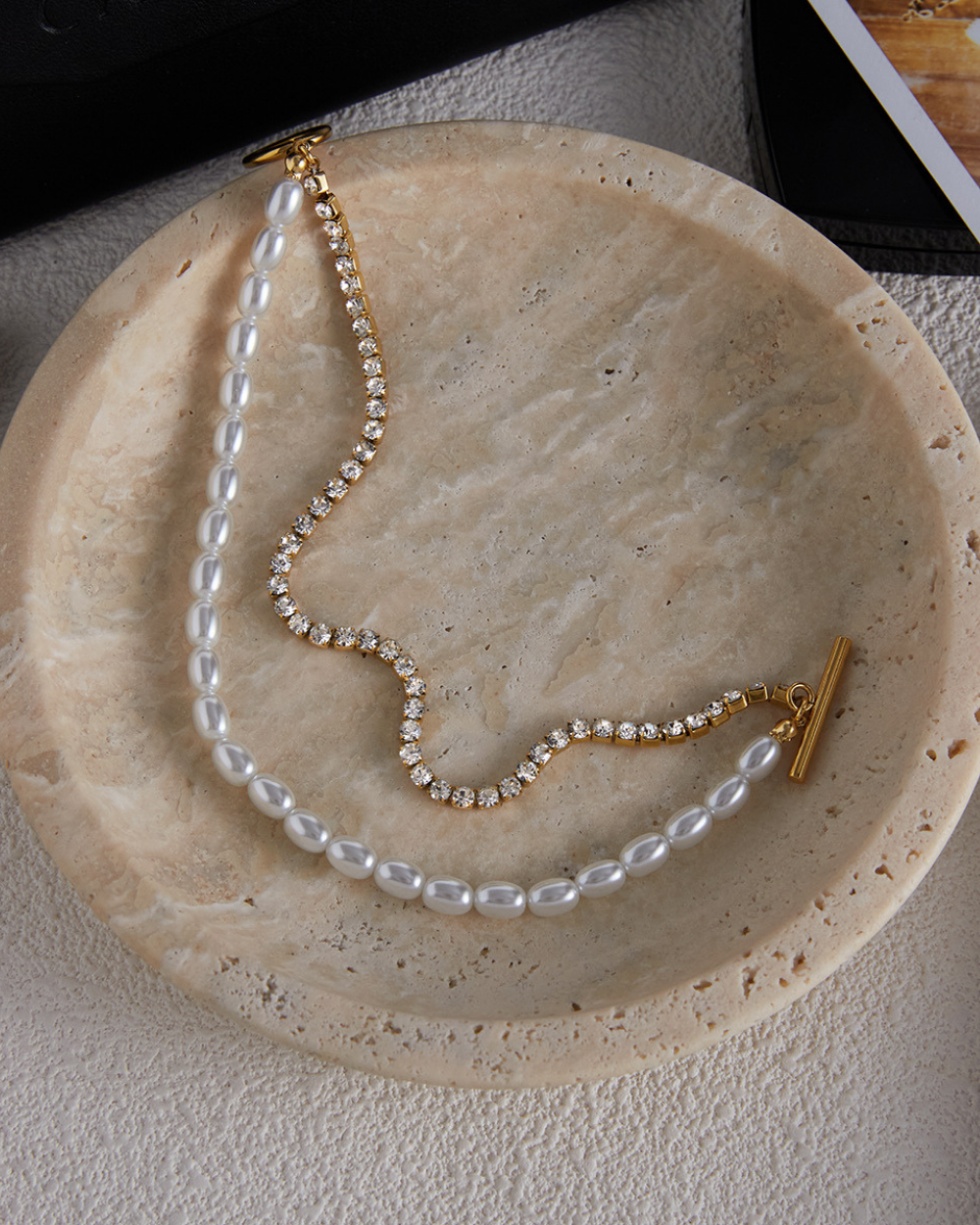 Pearl necklace with gold clasp on a stone surface