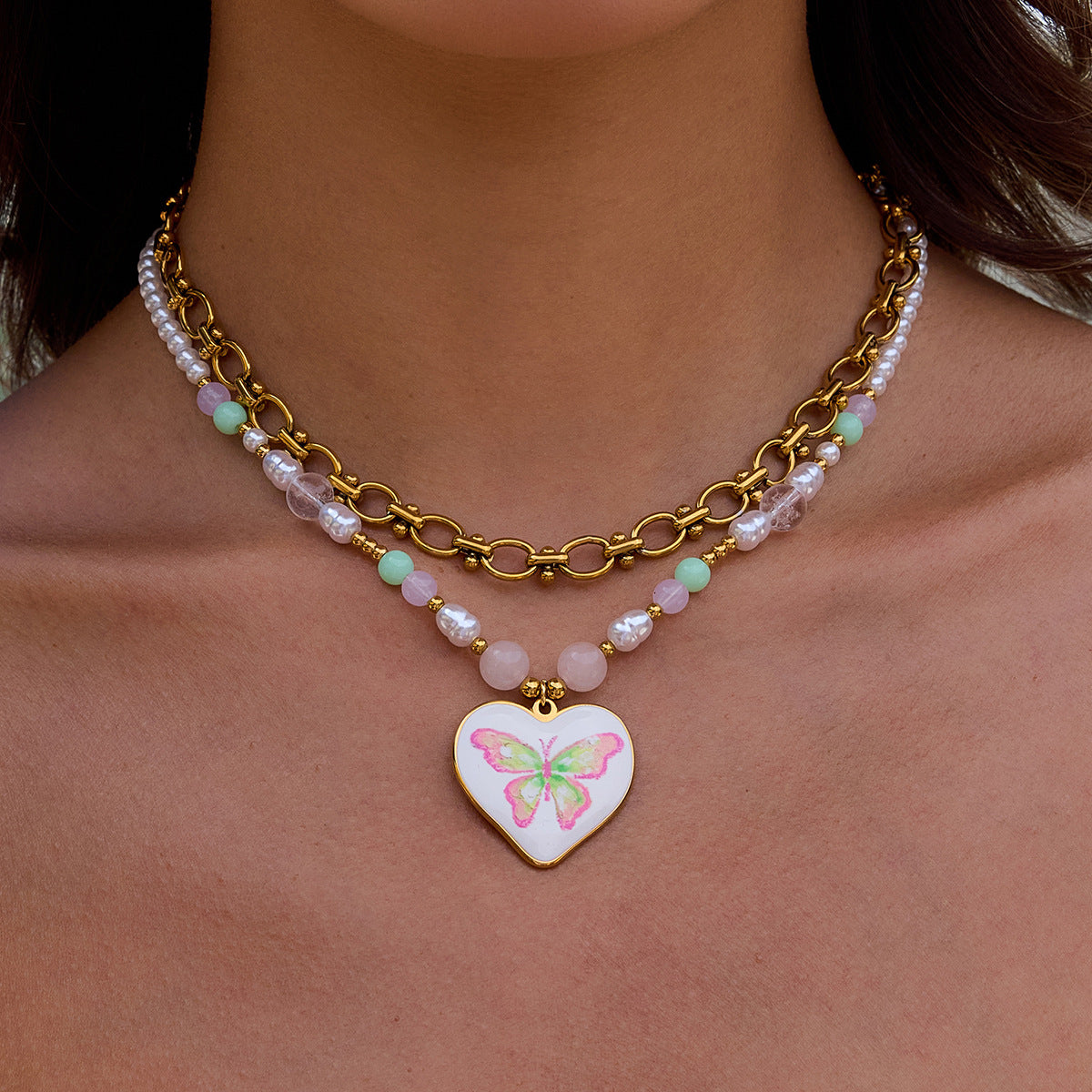 Model wearing heart butterfly necklace with gold chain and pearls