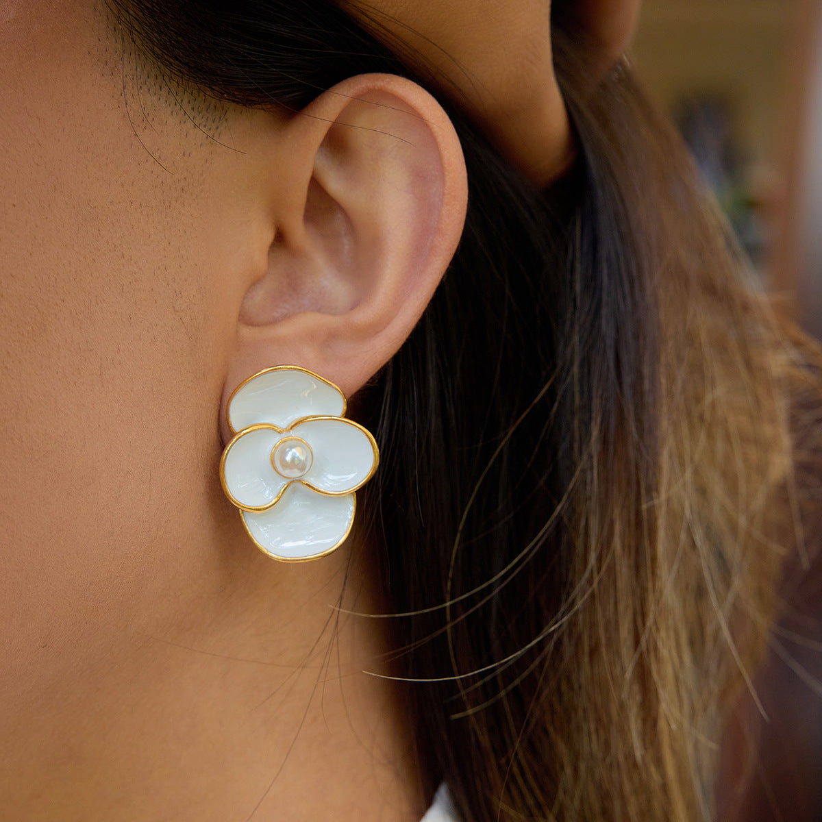Gold-edged petal earrings placed on white surface next to sunglasses