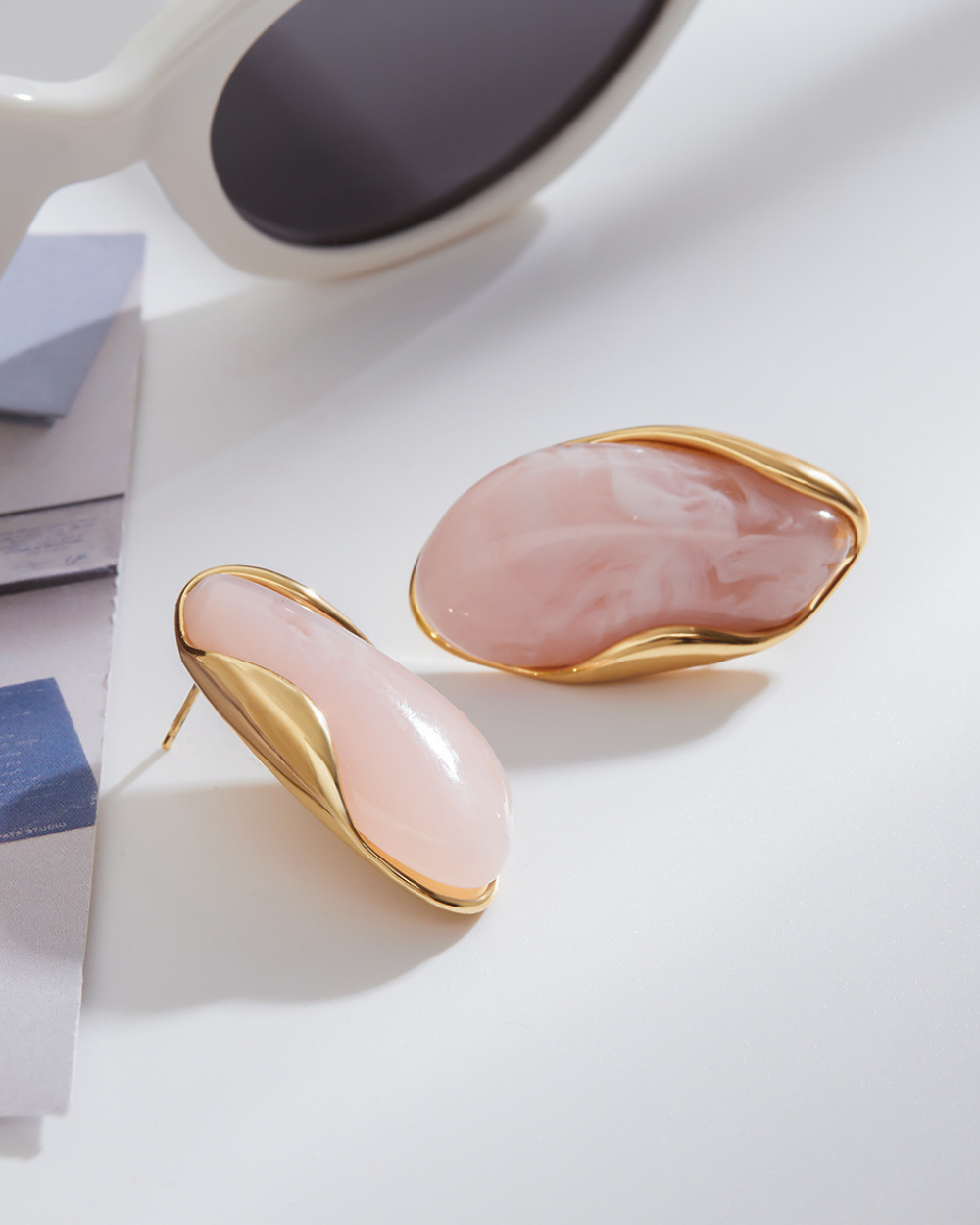 Pink earrings with gold accents on a light background