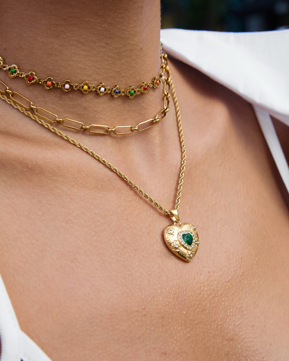 Close-up of a person wearing multiple gold necklaces with heart pendants.