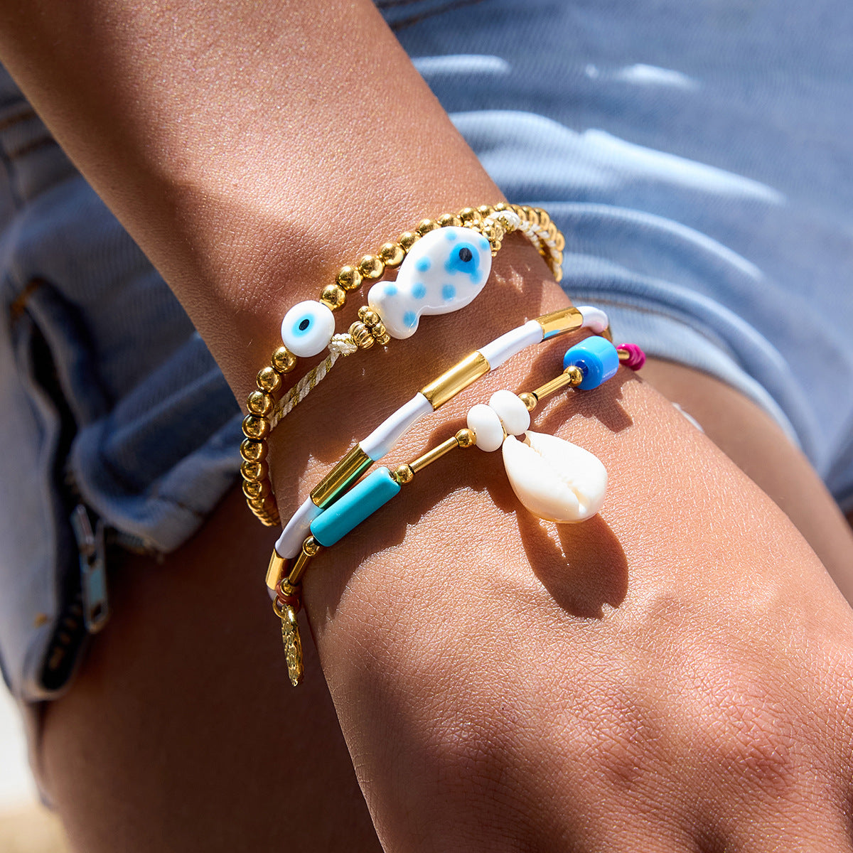 Close-up of a wrist wearing multiple colorful bracelets with beads and charms.
