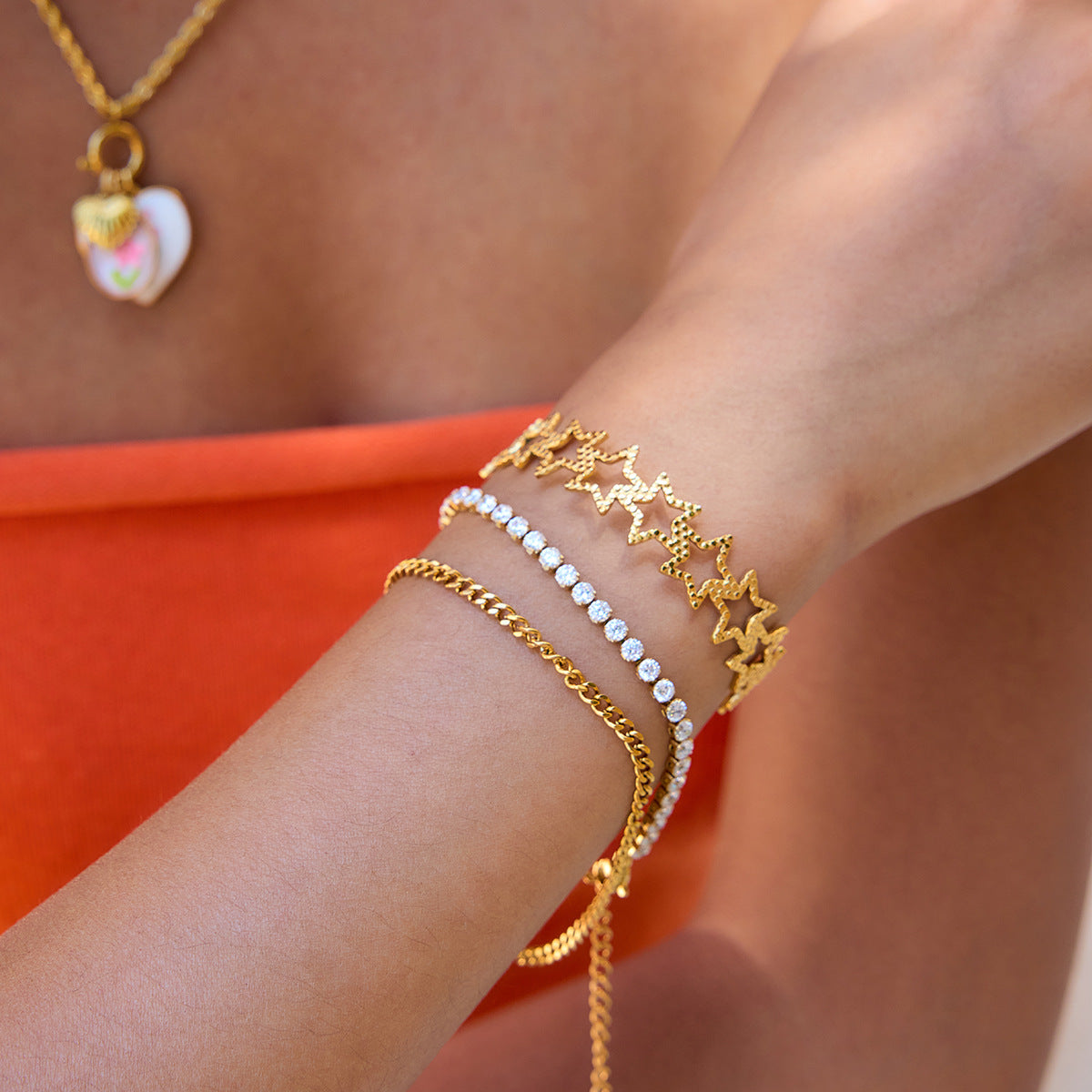 Model wearing gold star bracelet with orange top