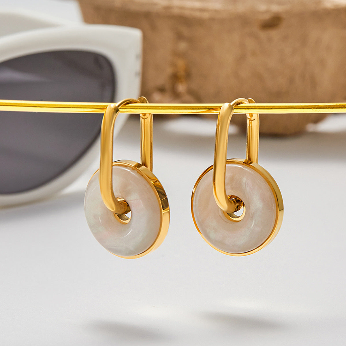 gold hoop earrings with white circular shell charm