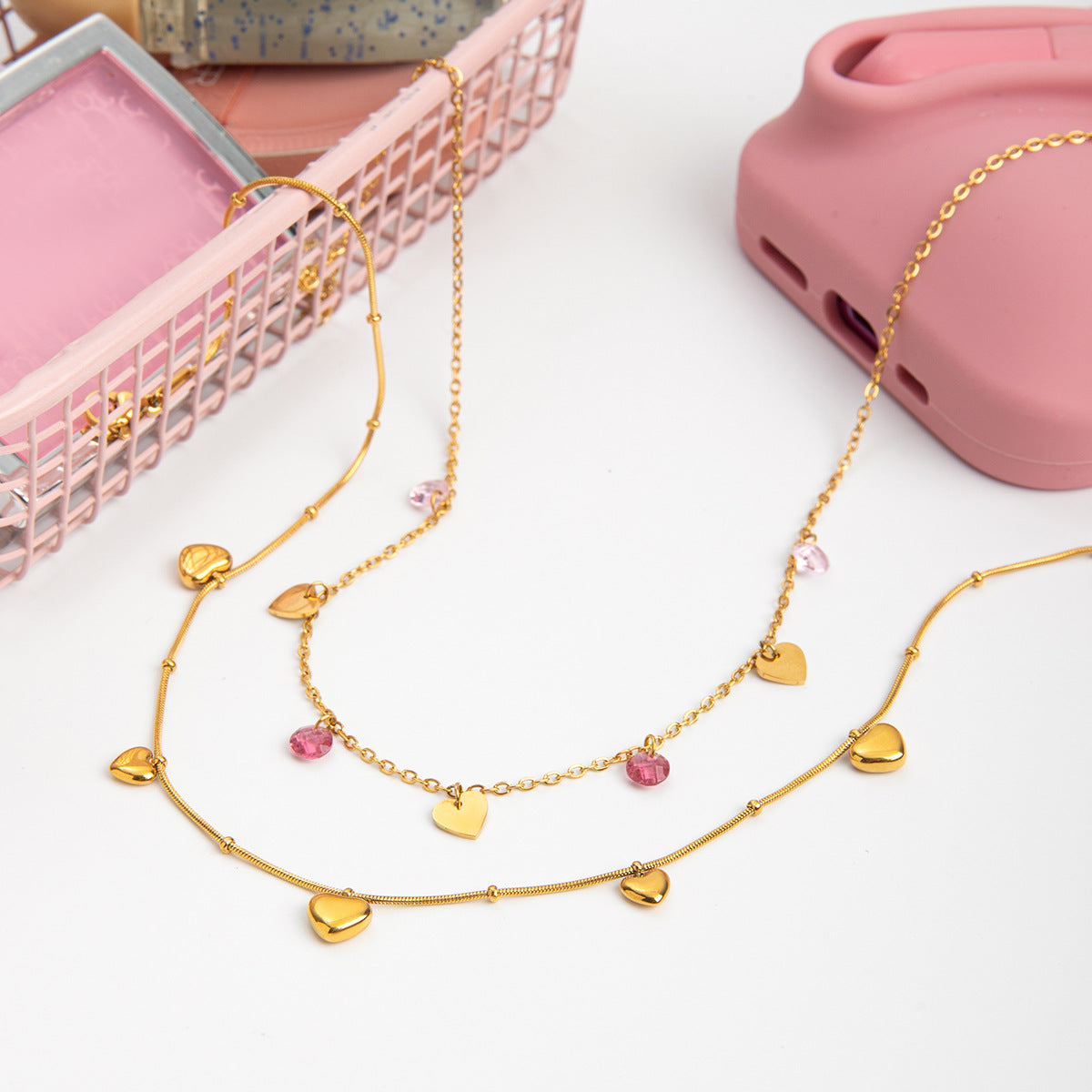 Gold necklace with heart-shaped pendants on a white surface