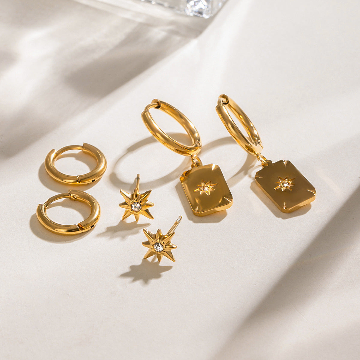 Golden earring trio with radiant starburst motifs and minimalist round hoops