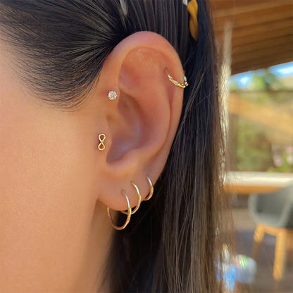Model wearing delicate 14k gold-plated infinity stud earrings, with a close-up of the earring in the ear for a modern, minimalistic look.