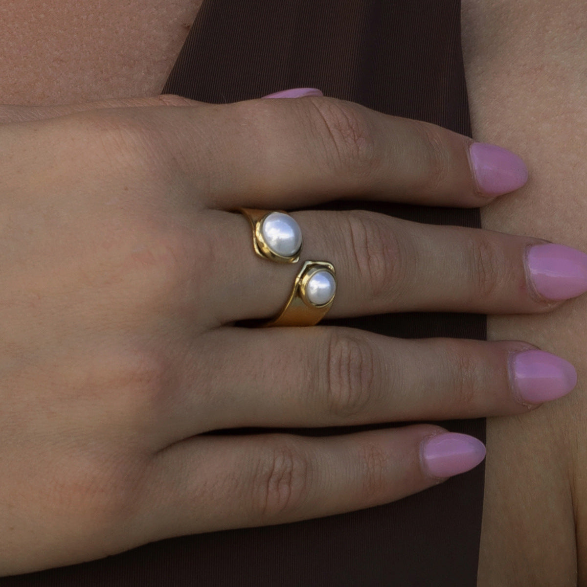 woman wearing pearl wrap ring on finger with brown top