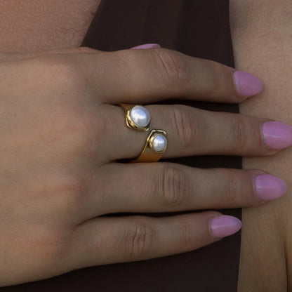 woman wearing pearl wrap ring on finger with brown top