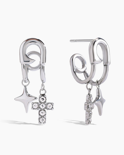 Pair of silver earrings with star, cross, and arrowhead charms on a white background