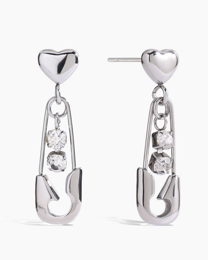 Silver earrings with heart tops and hanging diamond-like stones on a white background
