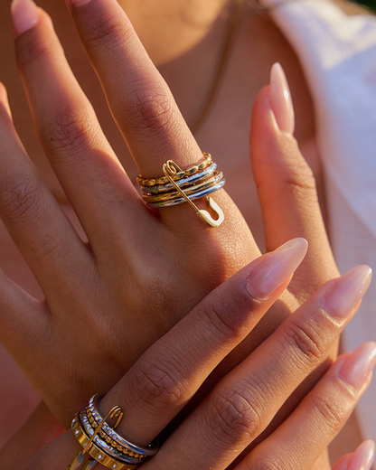 Close-up of a hand wearing multiple gold rings with a blurred background