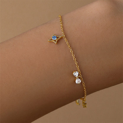 Close-up of a gold-plated sterling silver bracelet worn on a wrist, highlighting the star and crystal charms.