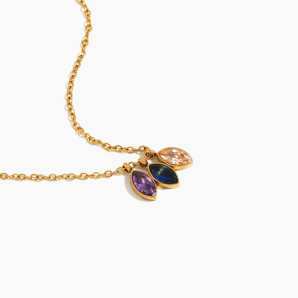 Gold necklace with three colorful gemstone pendants on a white background