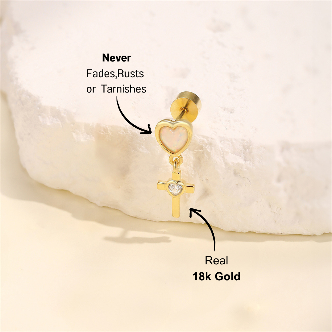 Close-up of 925 sterling silver heart cross earrings with opal and zirconia stones, plated in 14K gold, set against a white stone background.