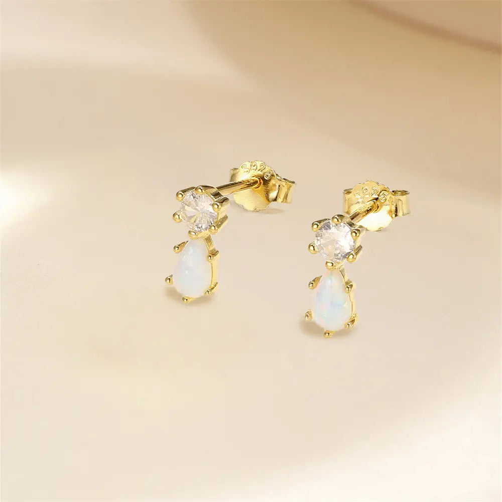 Close-up of 925 sterling silver opal teardrop stud earrings with zirconia accent, placed on a soft, light-colored background.