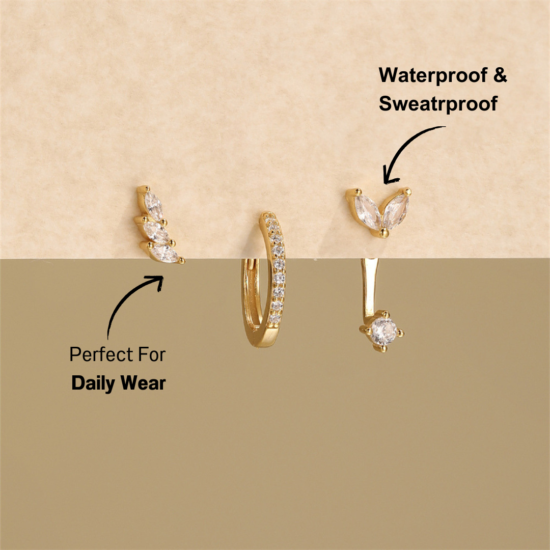 Gold-plated three-piece earring set featuring leaf design with zirconia stones, placed on neutral background.