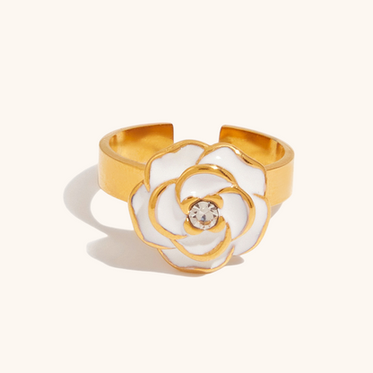 Front-facing product image of a gold-tone open ring featuring a sculpted white enamel flower