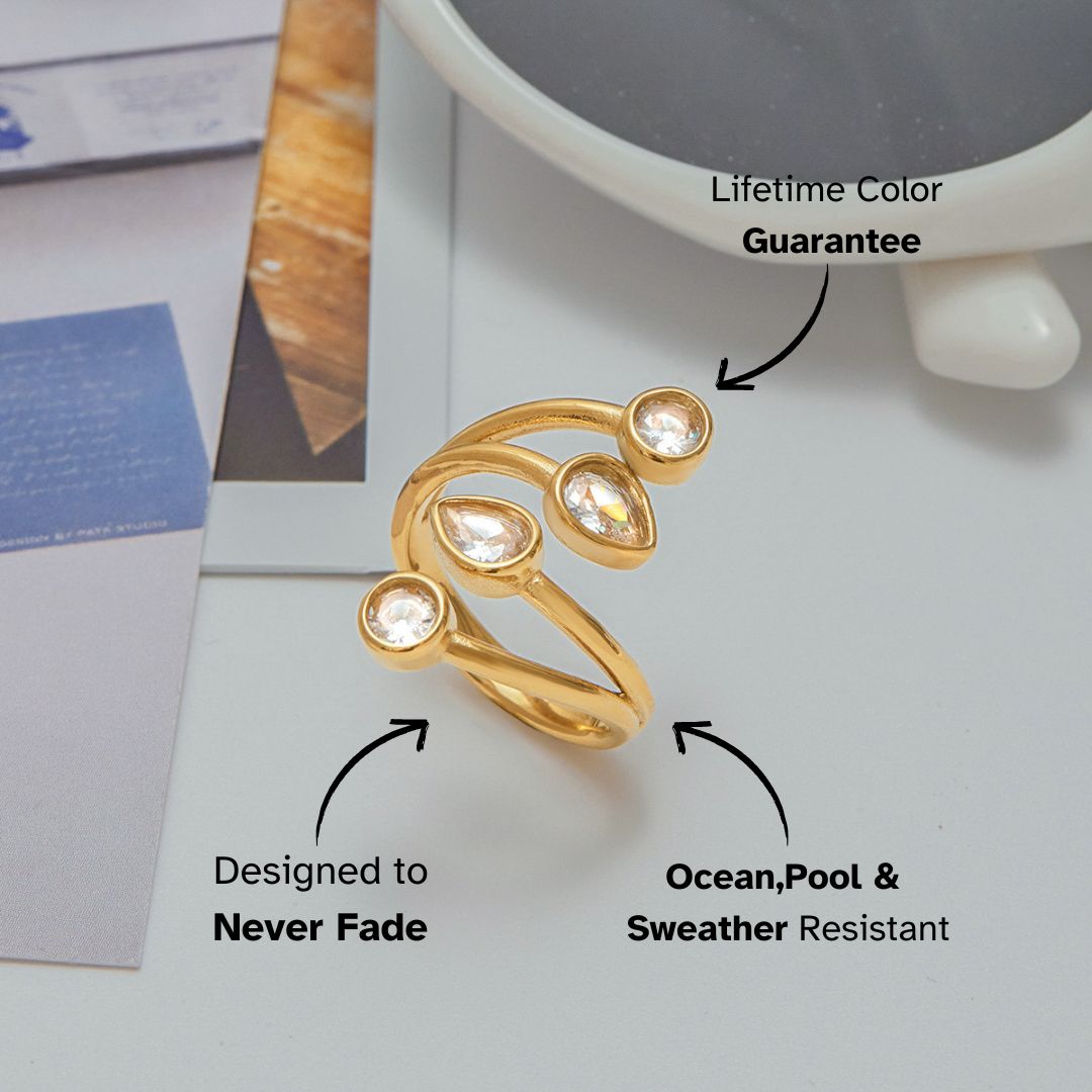 Gold open ring with teardrop and round crystals styled on a magazine